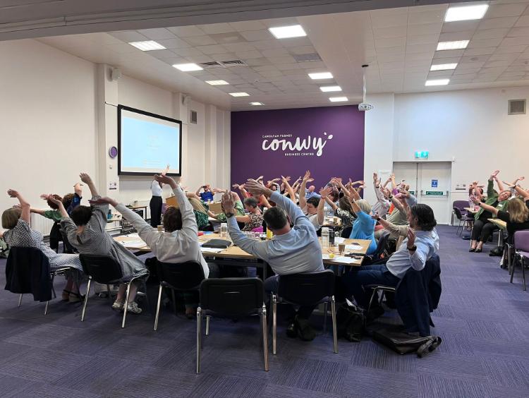 A group of adults doing seated yoga at a 2025 conference.