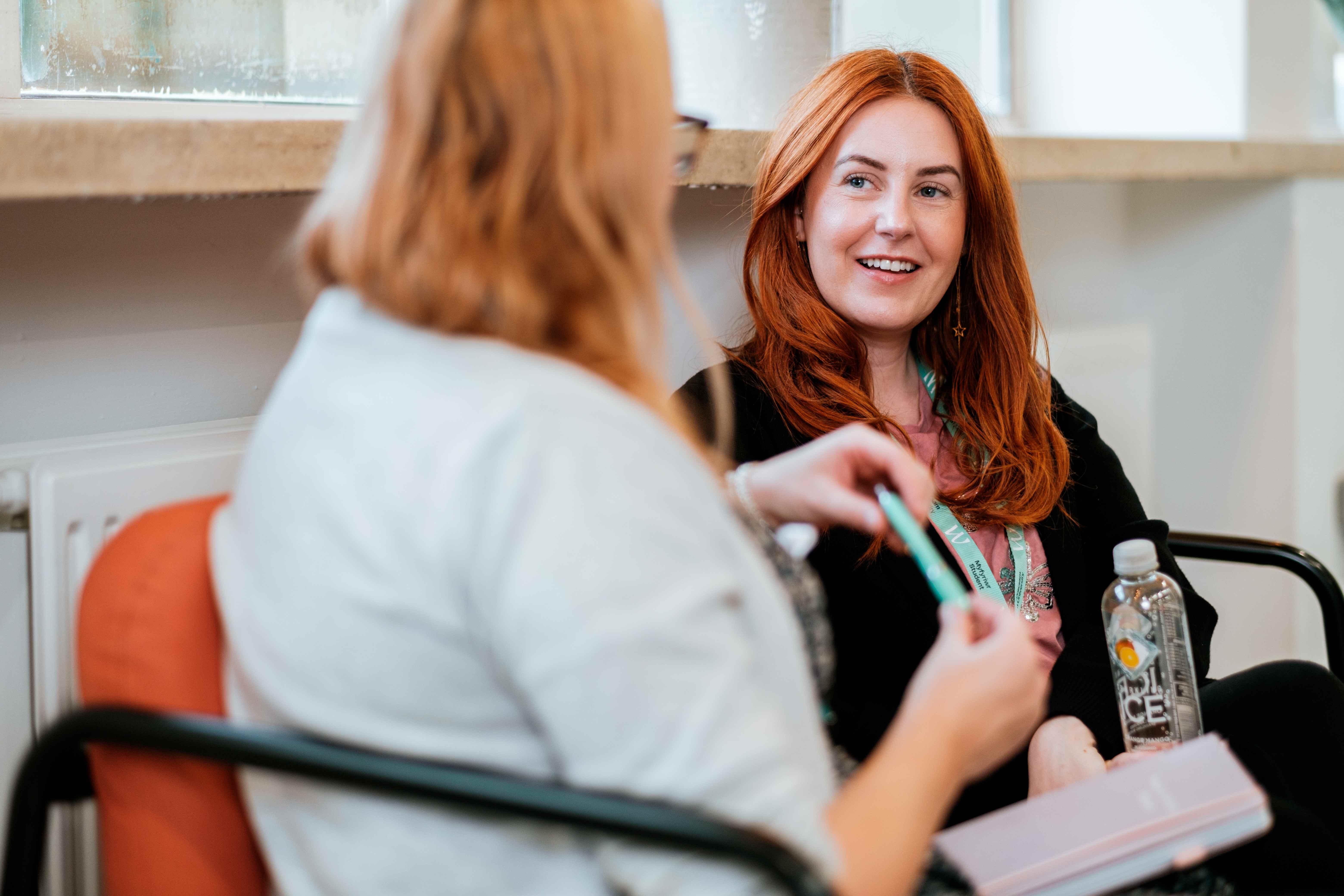 A student smiling whilst chatting with another student