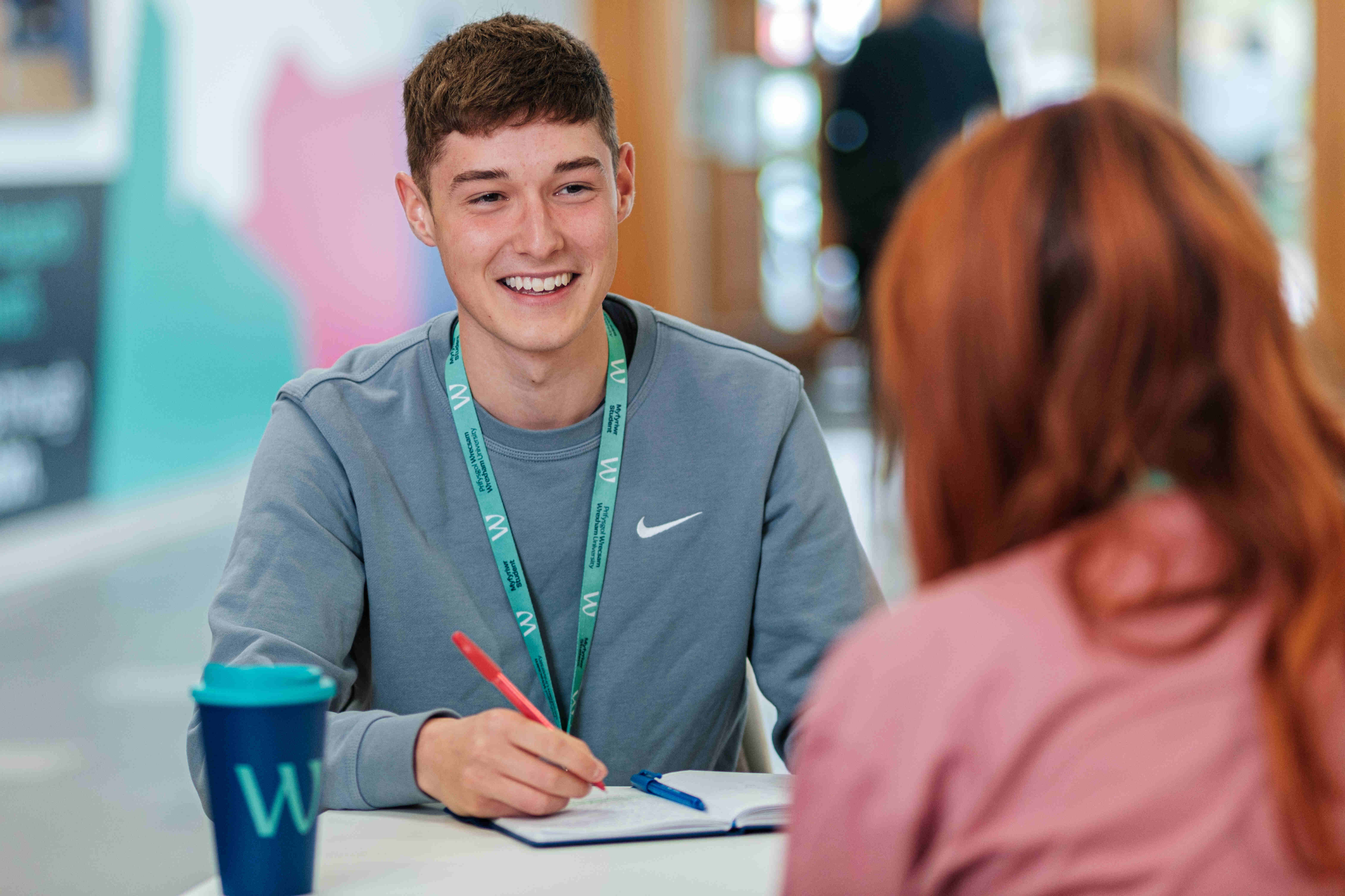 A student smiling and making notes