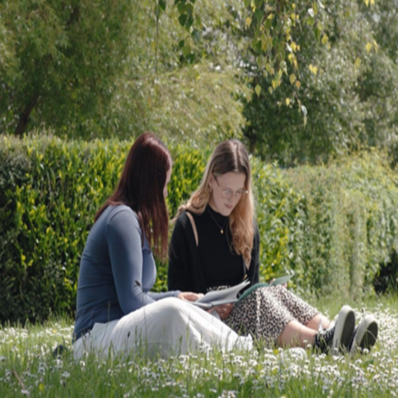 Two students sitting on grass reading