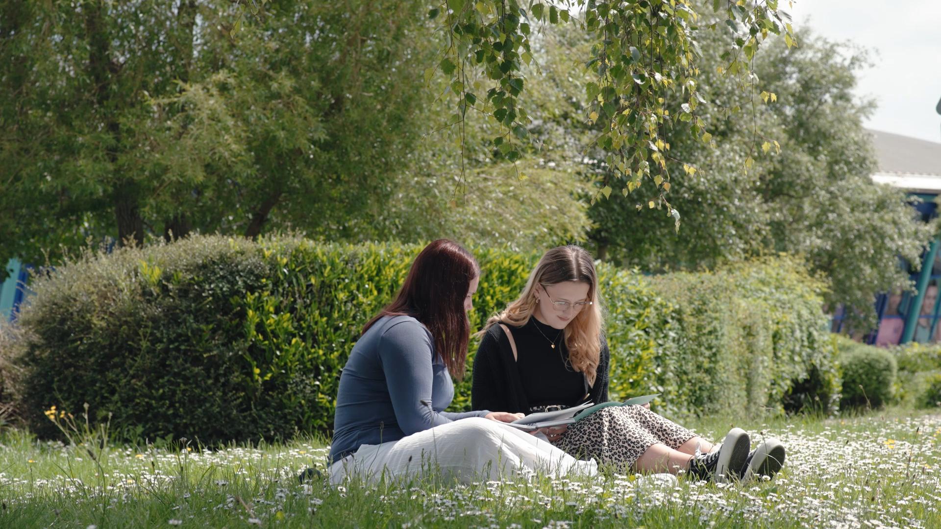 A student sitting on grass studying