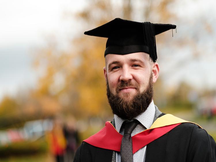 A graduate in his graduation cap and gown