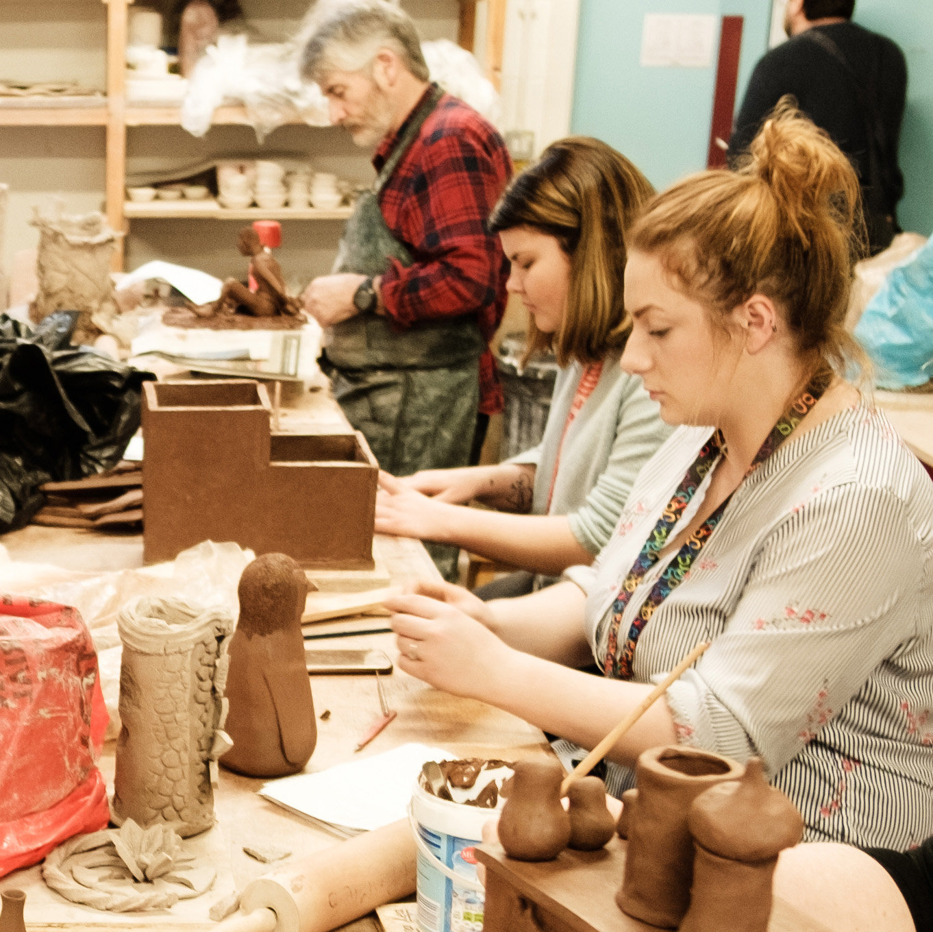 Students sitting in a workshop, hand modelling ceramics