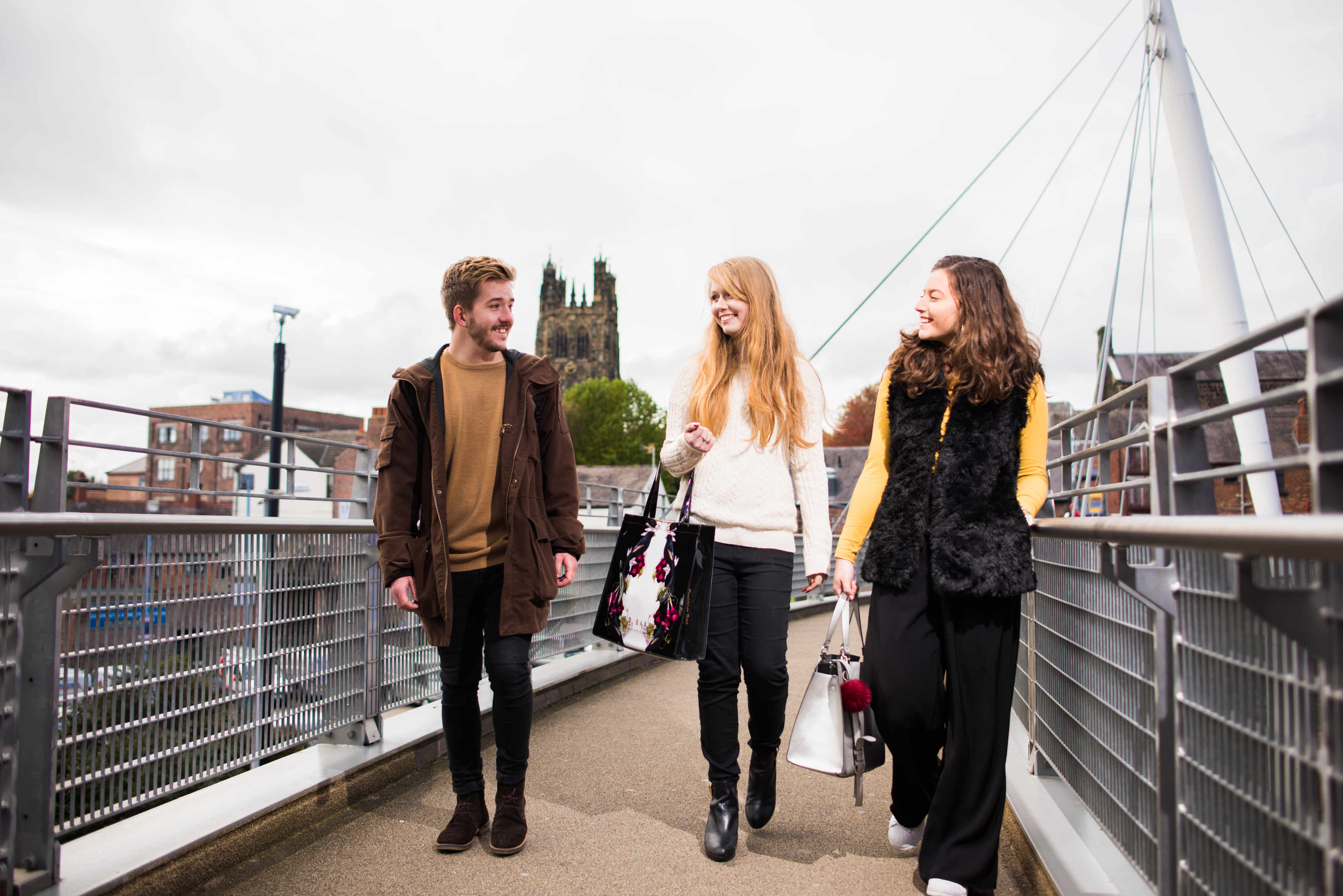 Students walking across bridge smiling