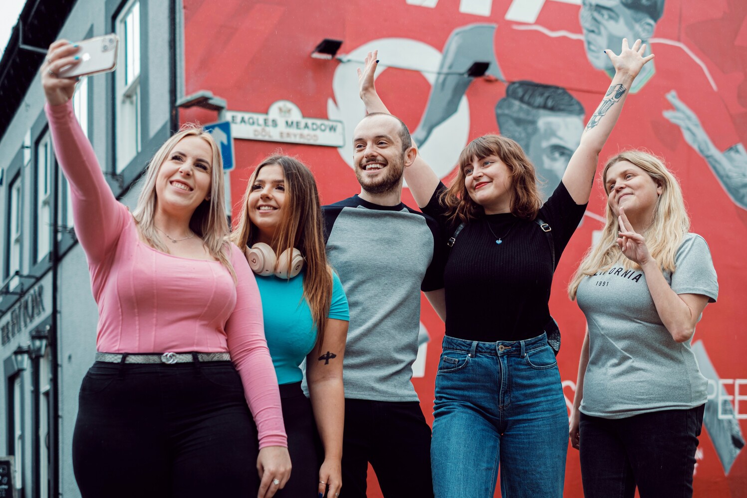 group of students smiling in front of mural