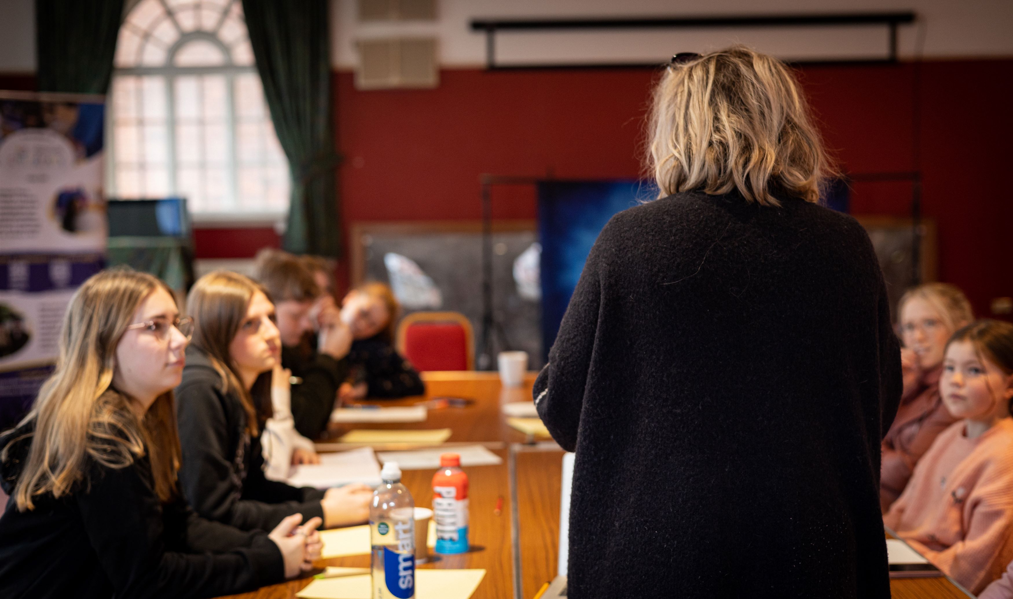 Teacher at top of table with kids sat down looking at her