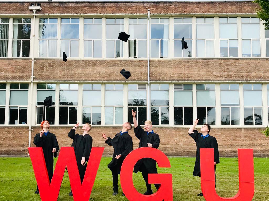 Boys in Graduation gowns throwing hats in air