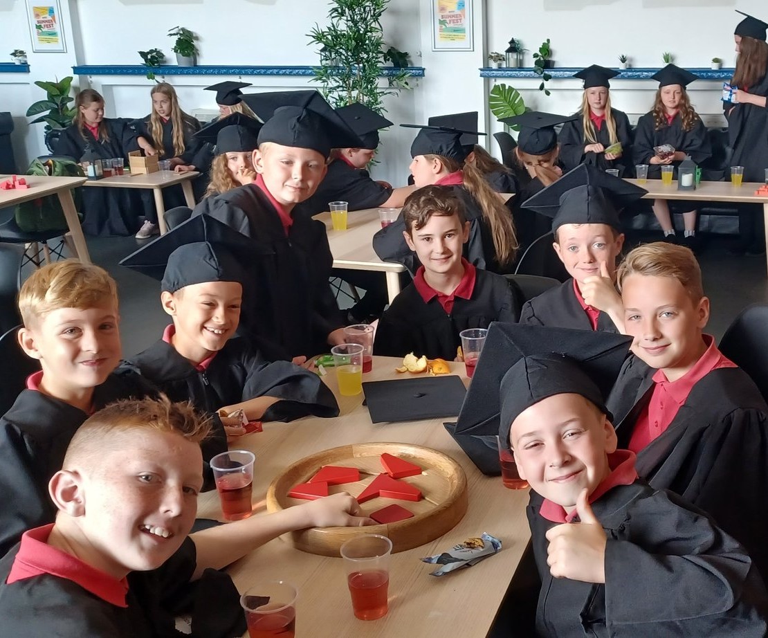 Children in graduation gowns around a game