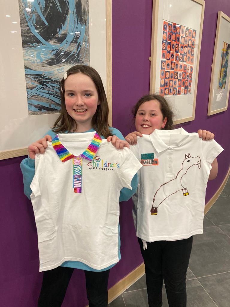 two girls with t shirts designed for childrens university
