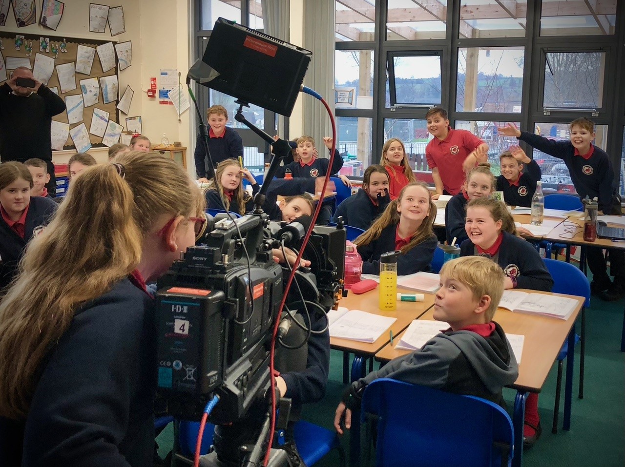School pupils are filmed by a pupil using a large video camera