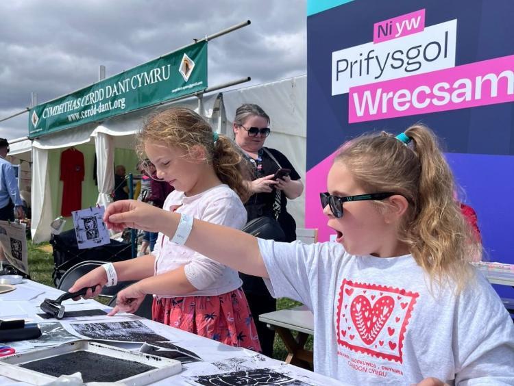An image of two young girls taking part in a Gresford Disaster Memorial workshop held by Wrexham University at the 2025 National Eisteddfod.