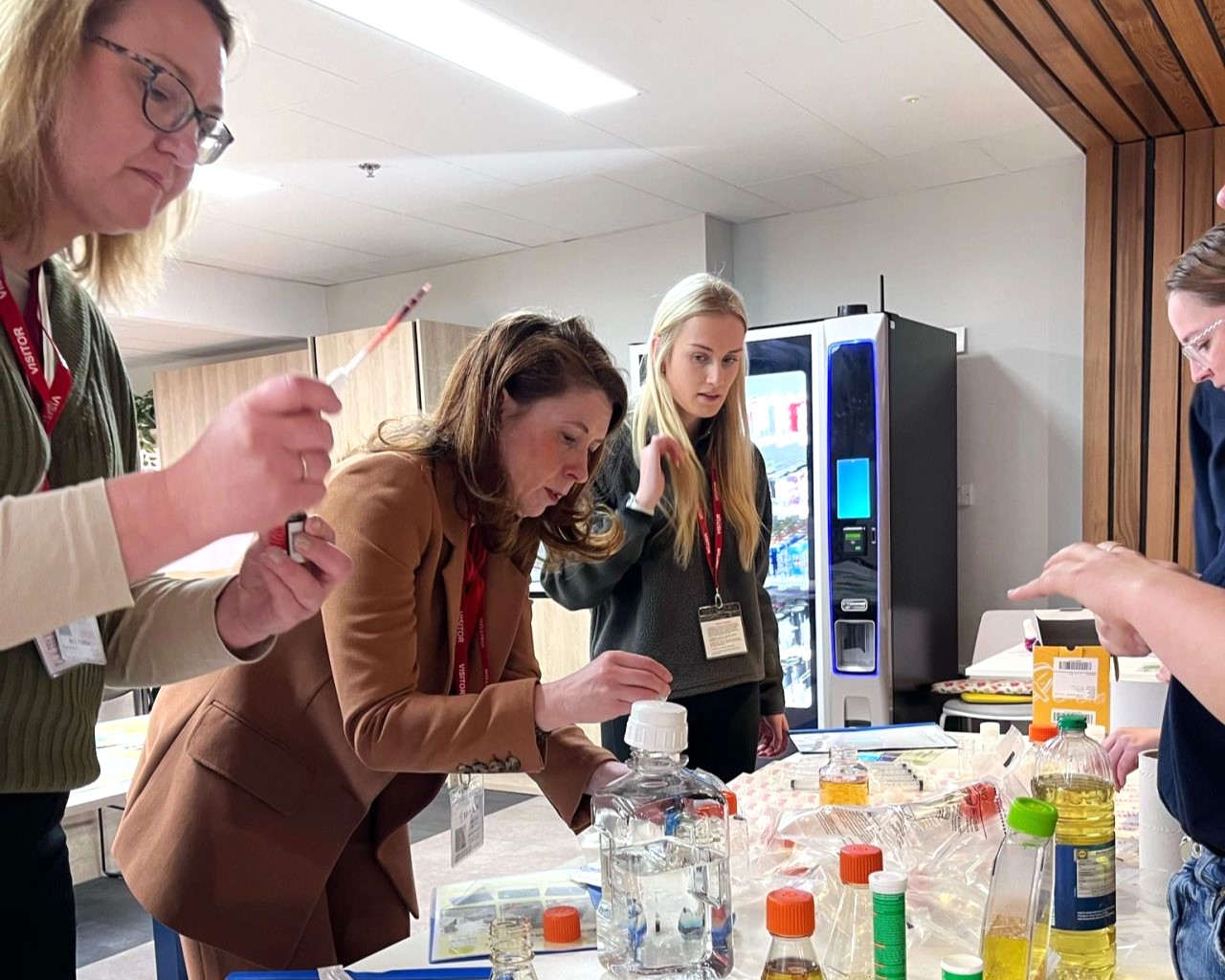 A group of teachers and Nina Ruddle stood together experimenting with scientific equipment.