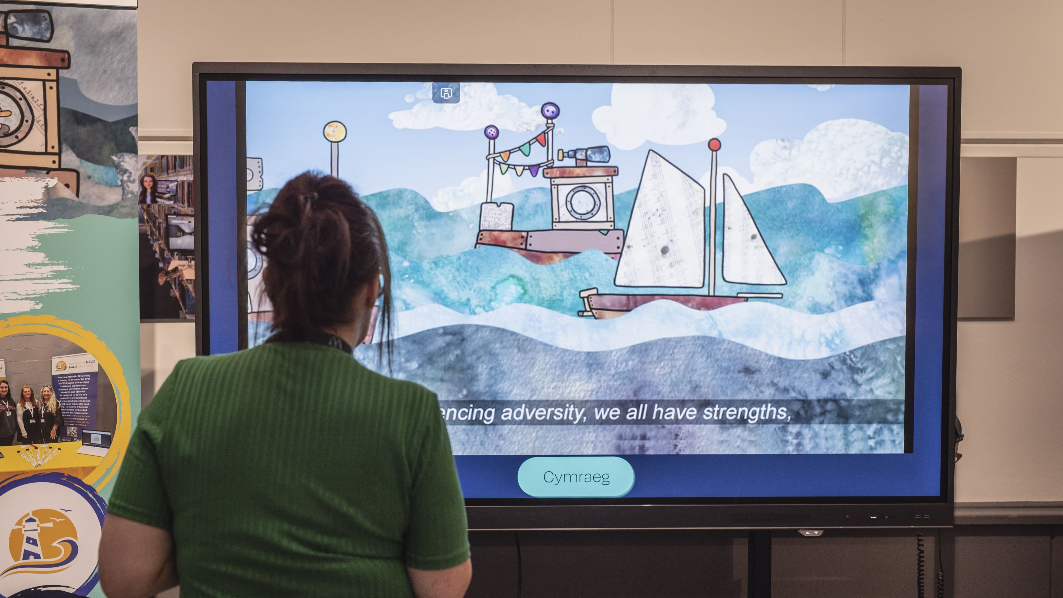 A person stood in front of a screen that is playing the TrACE Navigating the Storm video.