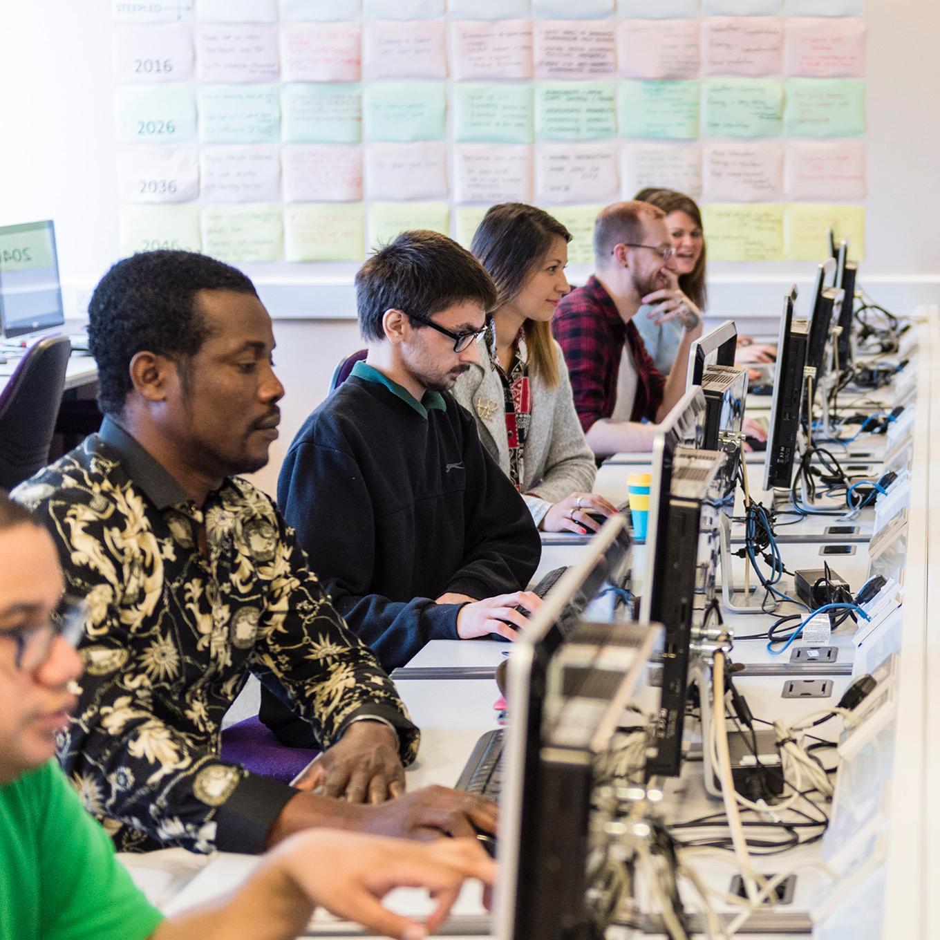 A row of computing students working in a computer lab