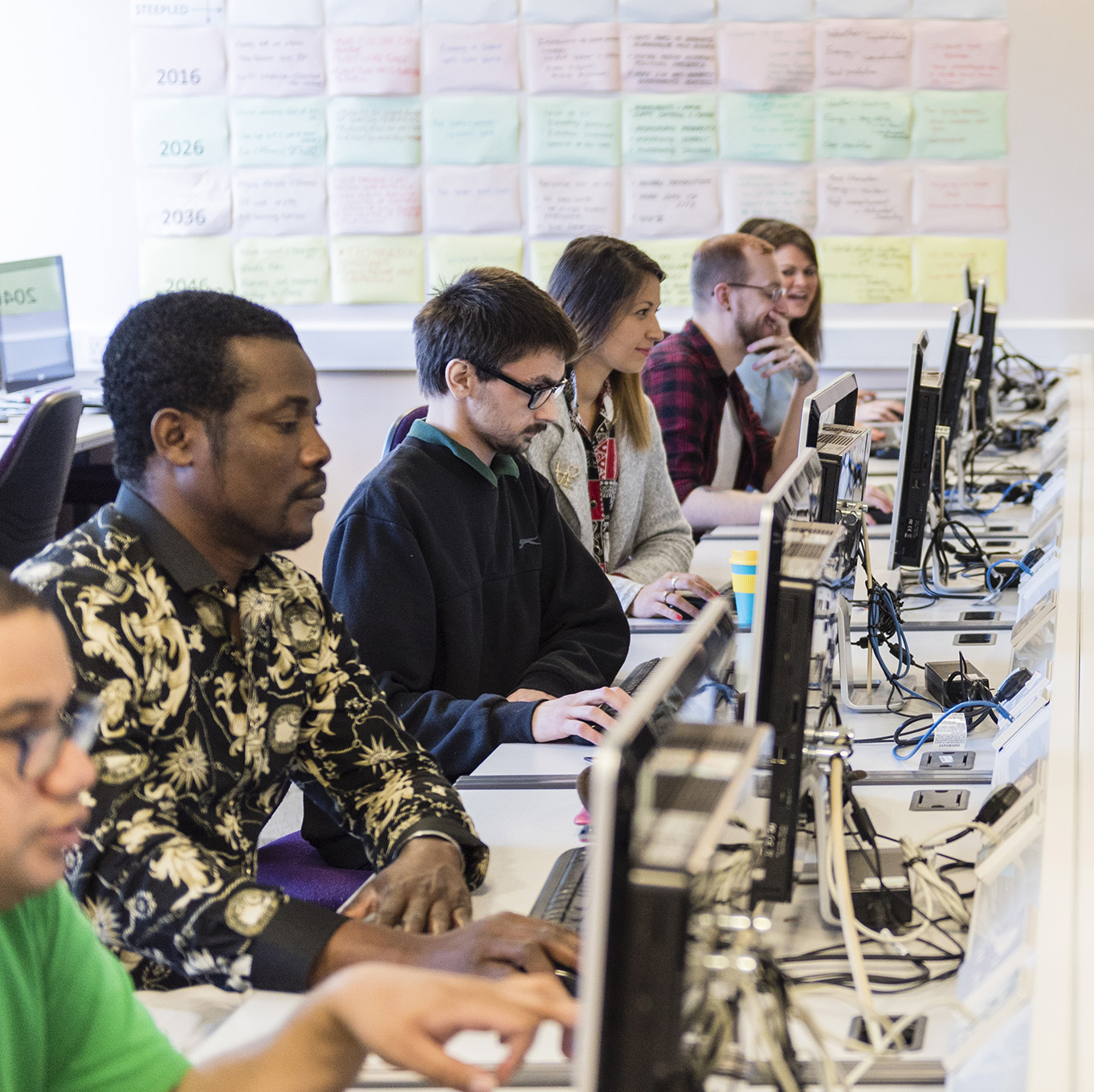 A row of computing students working in a computer lab