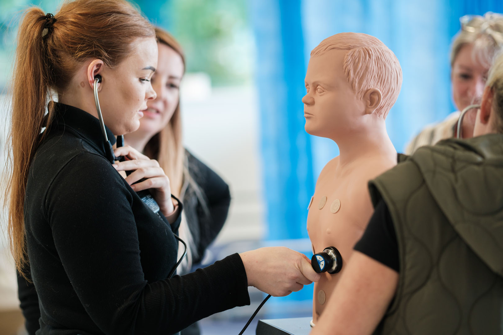 Students monitoring a dummy using stethoscope equipment