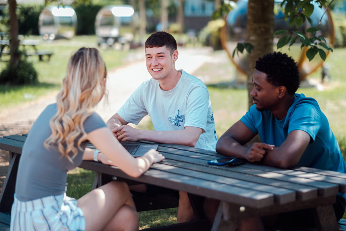 Three students sitting in the sun having a conversation