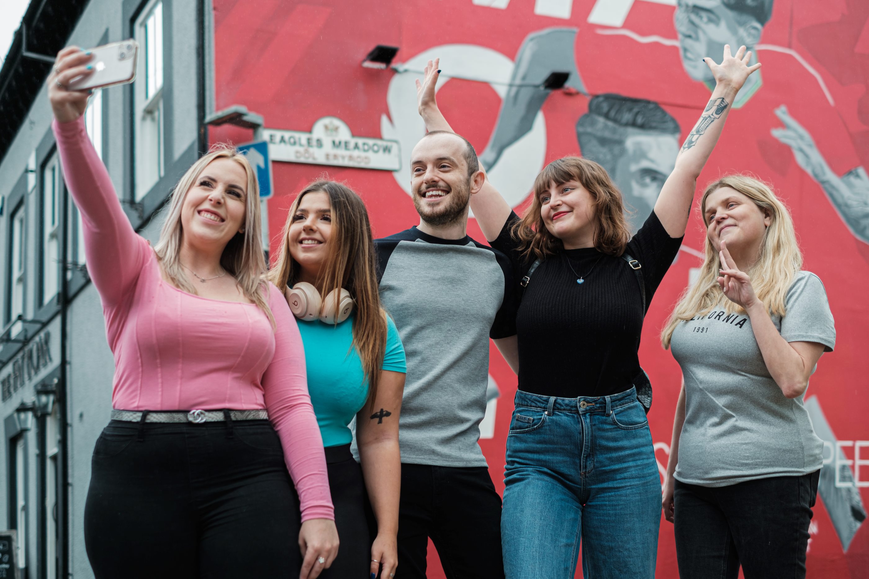 Students taking selfie by football wall
