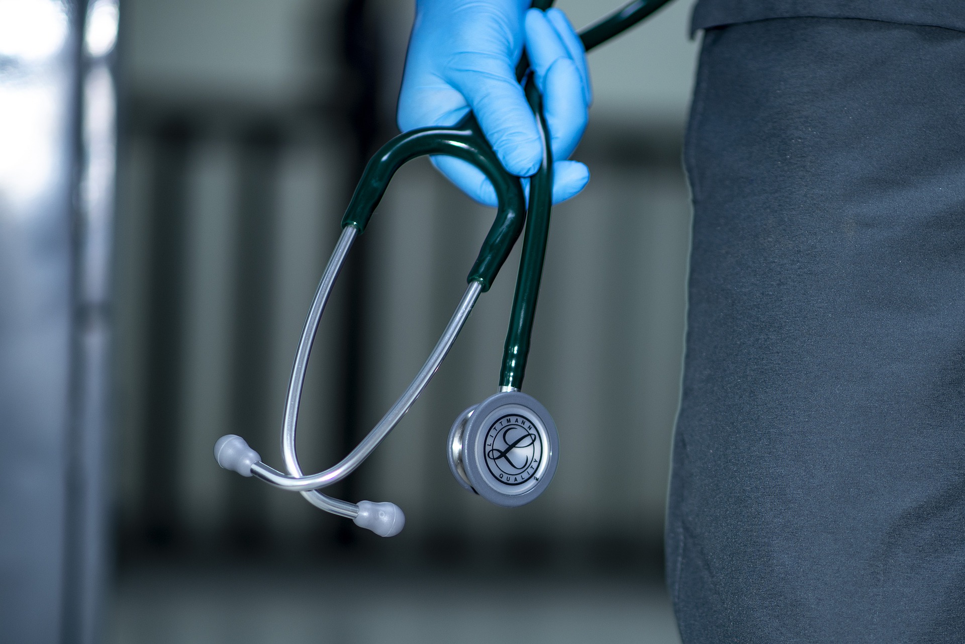 A stethoscope held in a blue gloved hand