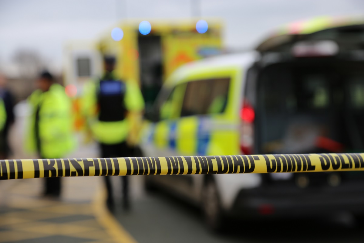 Crime scene tape with police car in background