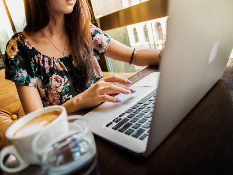 Person using a laptop with beverages next to them.