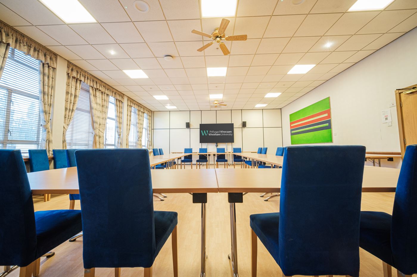 A boardroom layout facing a large screen on the wall