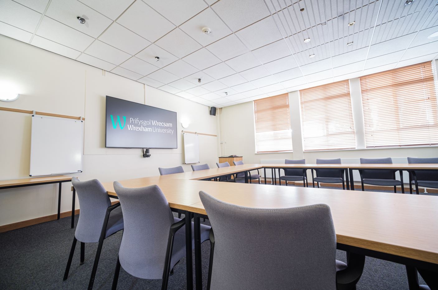 A boardroom layout with a large screen on the wall