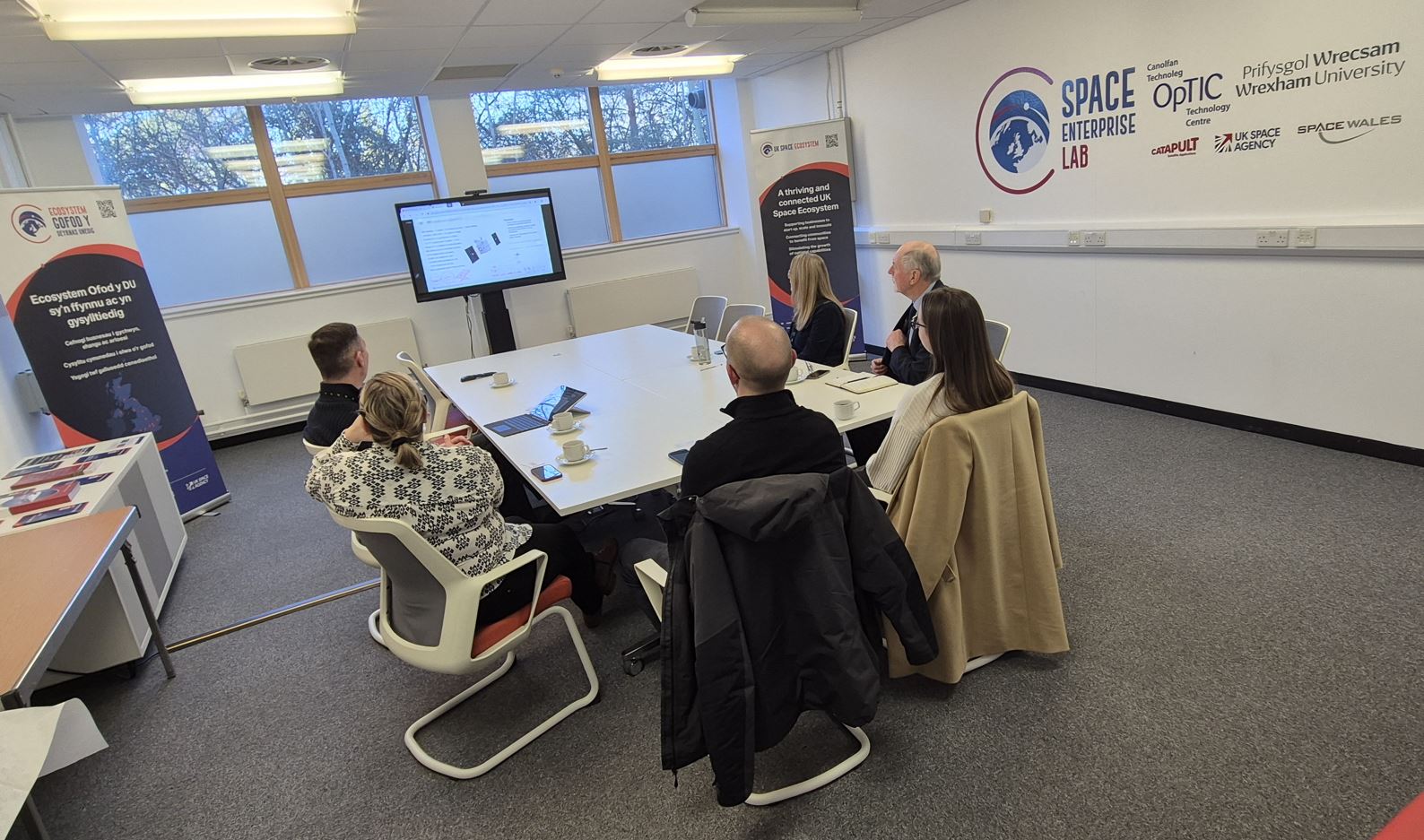 A small group of people sat watching a presentation