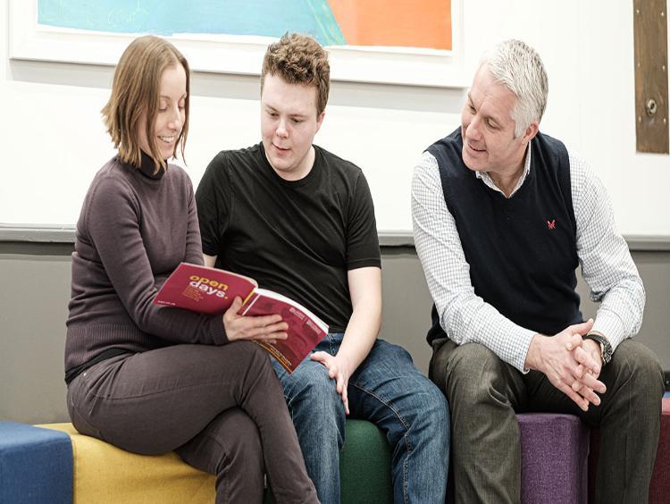 Parents looking at a prospectus with their son