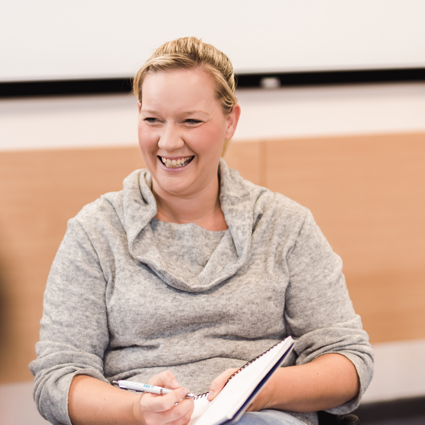 A counselling student smiles, her notebook open on her lap