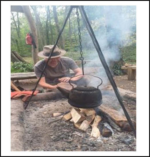 Person heating a kettle on camp fire