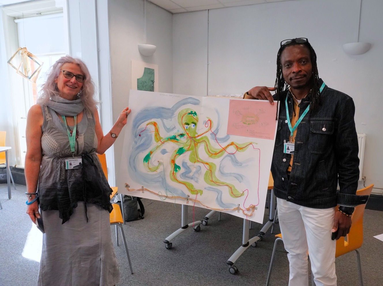 Two researchers holding an drawn image of an octopus