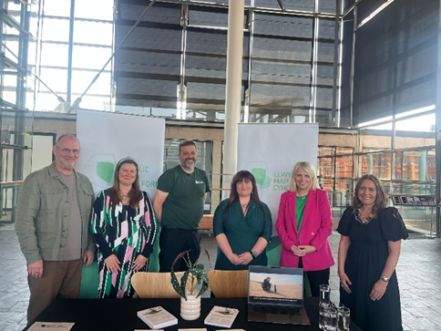 Group of researchers stood behind a table looking at the camera at an event