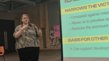 Female Researcher presenting in front of a large screen