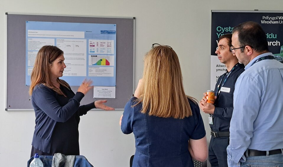 tanya standing next to their poster presenting to interested people
