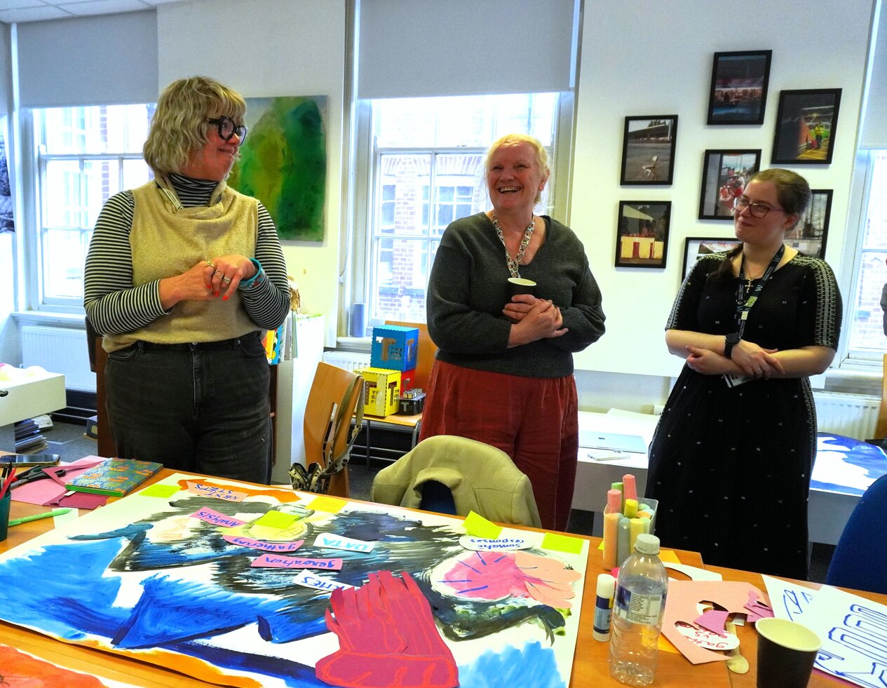 three people talking and smiling with a painting