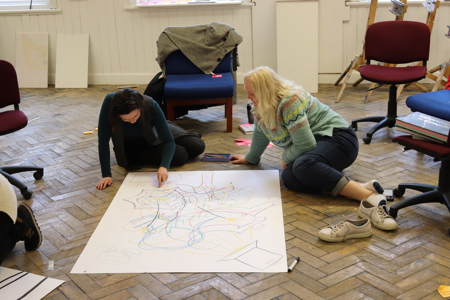 Two people creating artwork on the floor