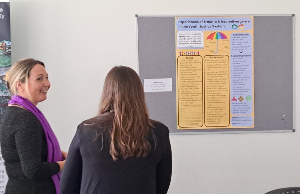 two people chatting in front of a poster on the wall