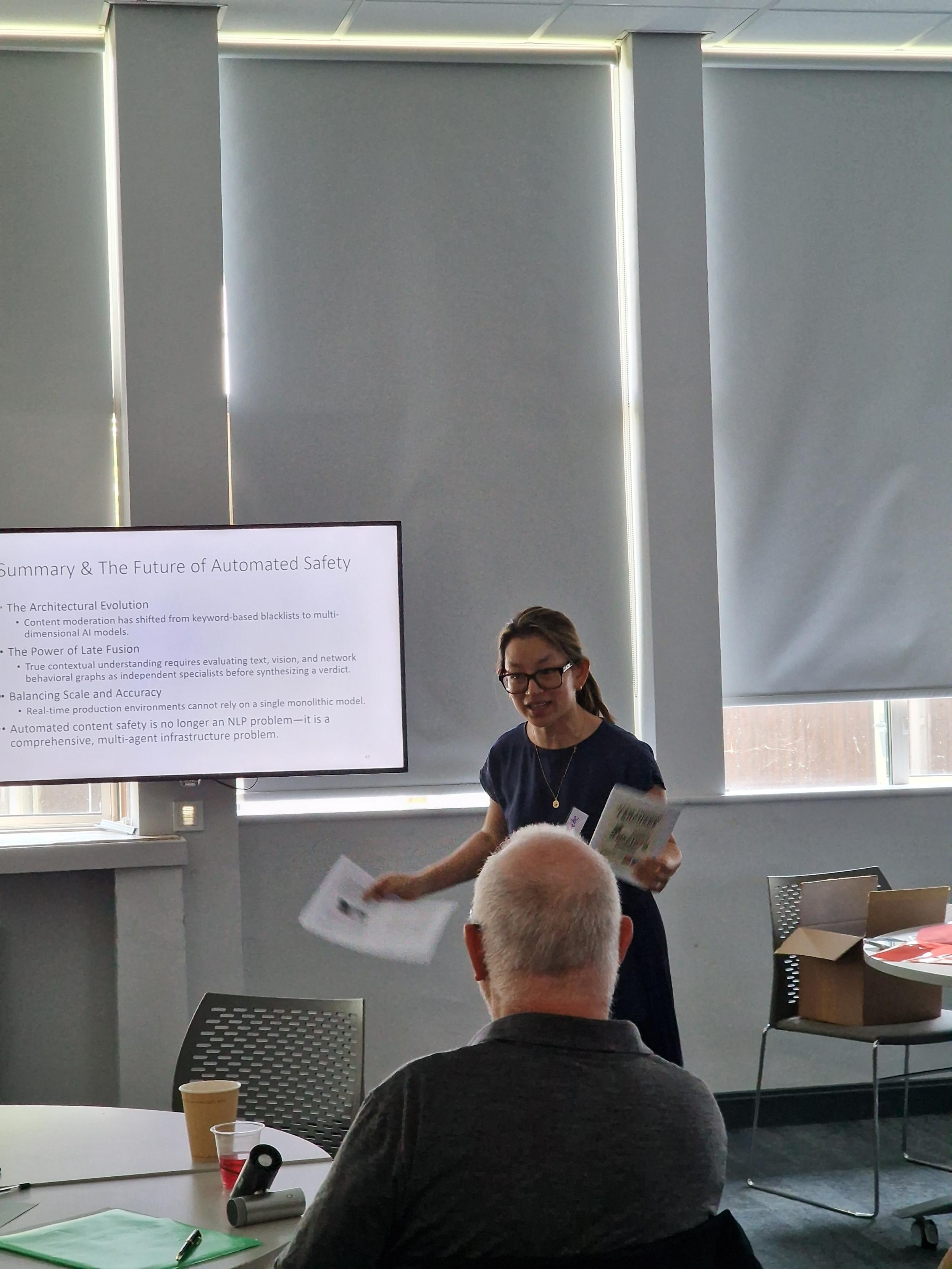 Presenter holding booklets talking to a class room