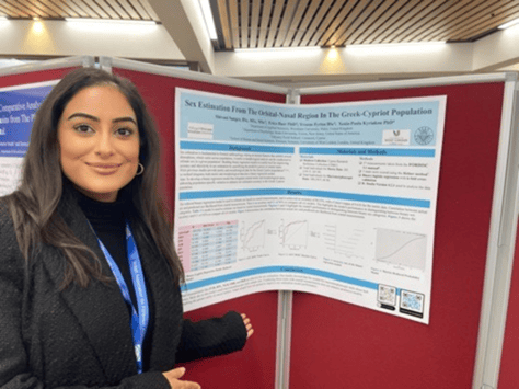 Research student standing in front of poster presentation at a conference