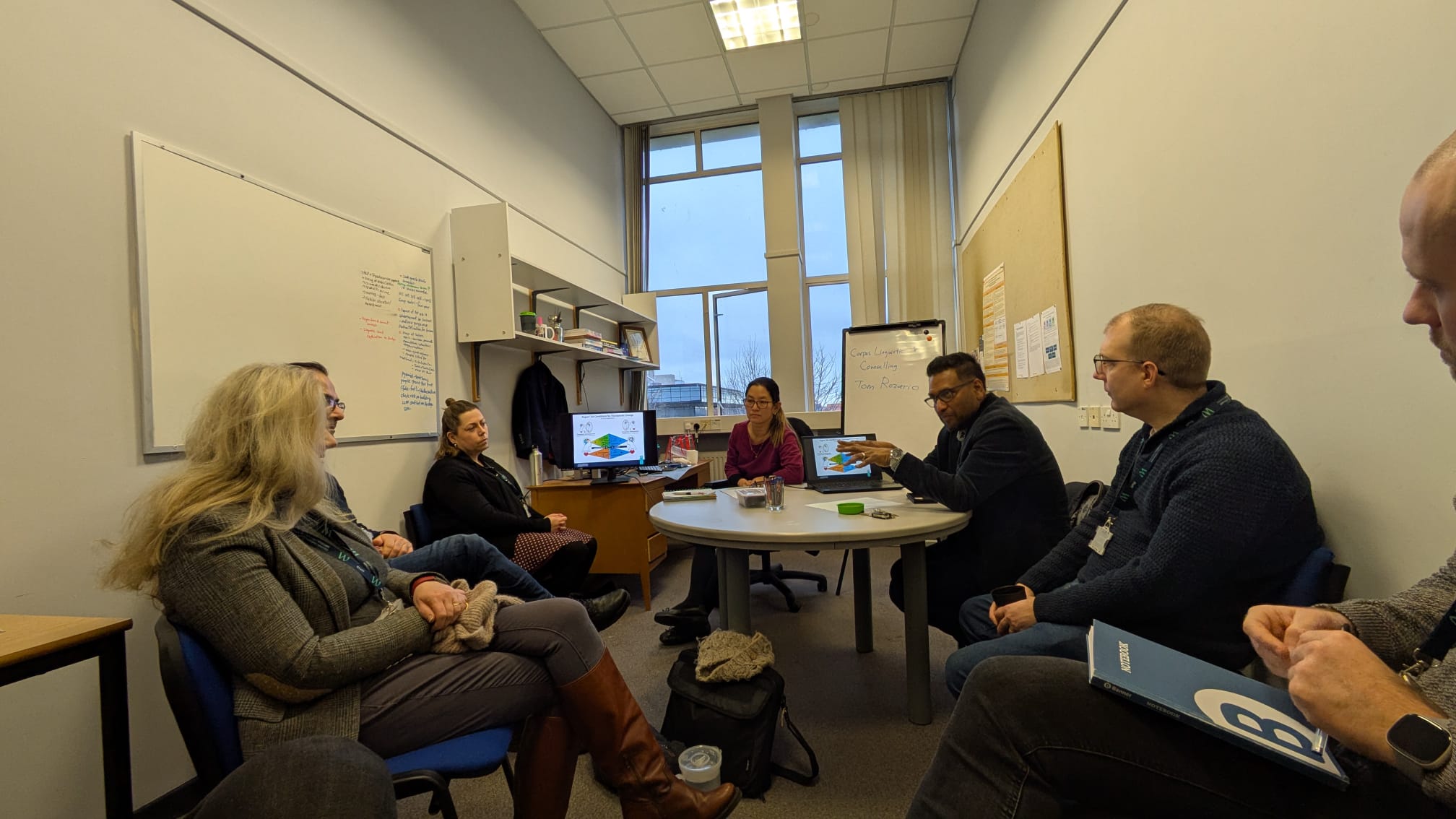 Colleagues sat in a room listening to a speaker who is also sat down