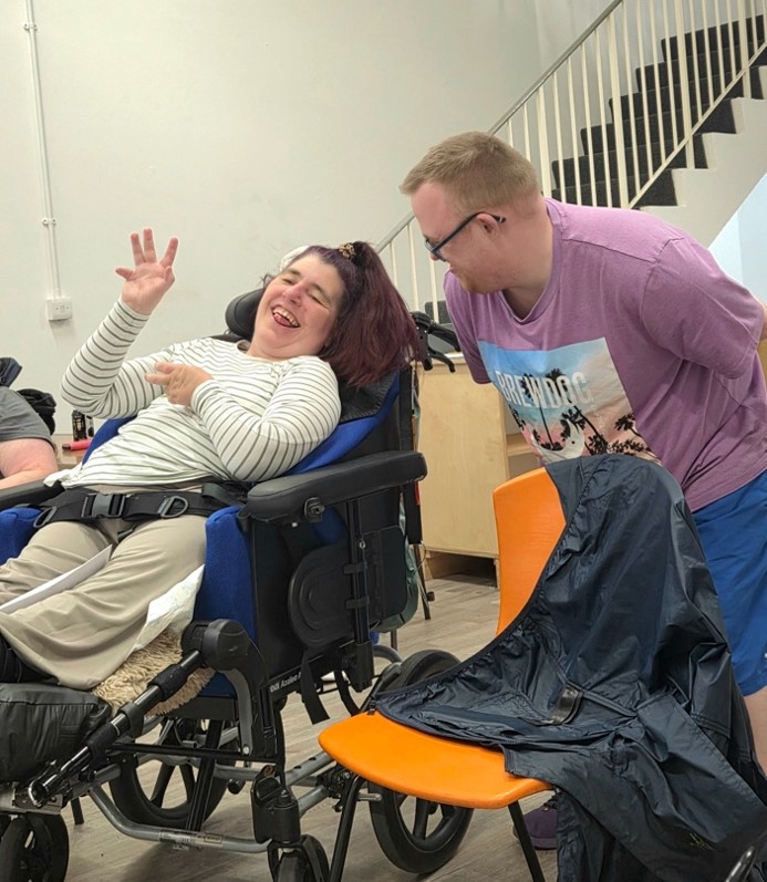 Two theatre performers interacting, one is a wheelchair user