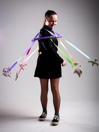 A girl dressed in black wearing horse brooches on ribbon on a hoop