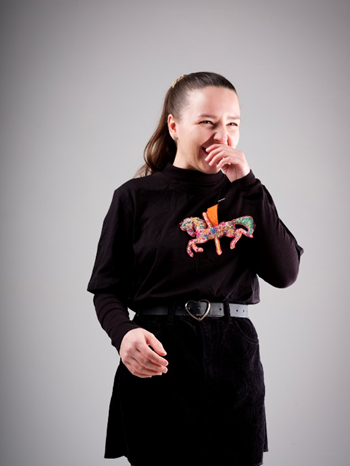 A girl dressed in black wearing horse brooches on a jumper