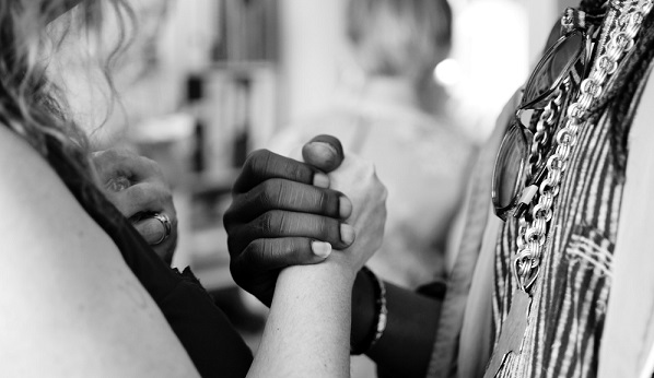 2 people holding hands black and white