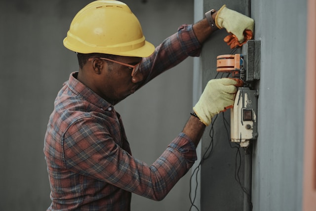 a worker in a yellow hard hat doing something with electrics