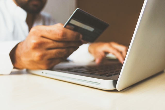 a hand with a credit card at a laptop