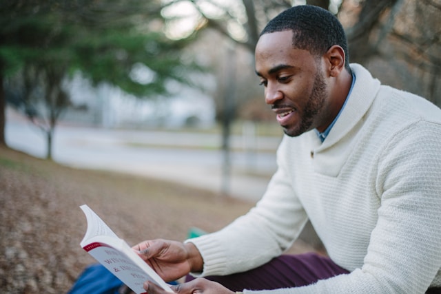 man sitting outside reading a book