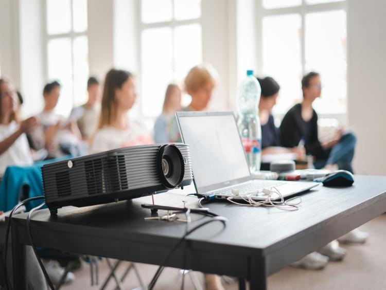 People in a class room with a laptop and projector in the foreground