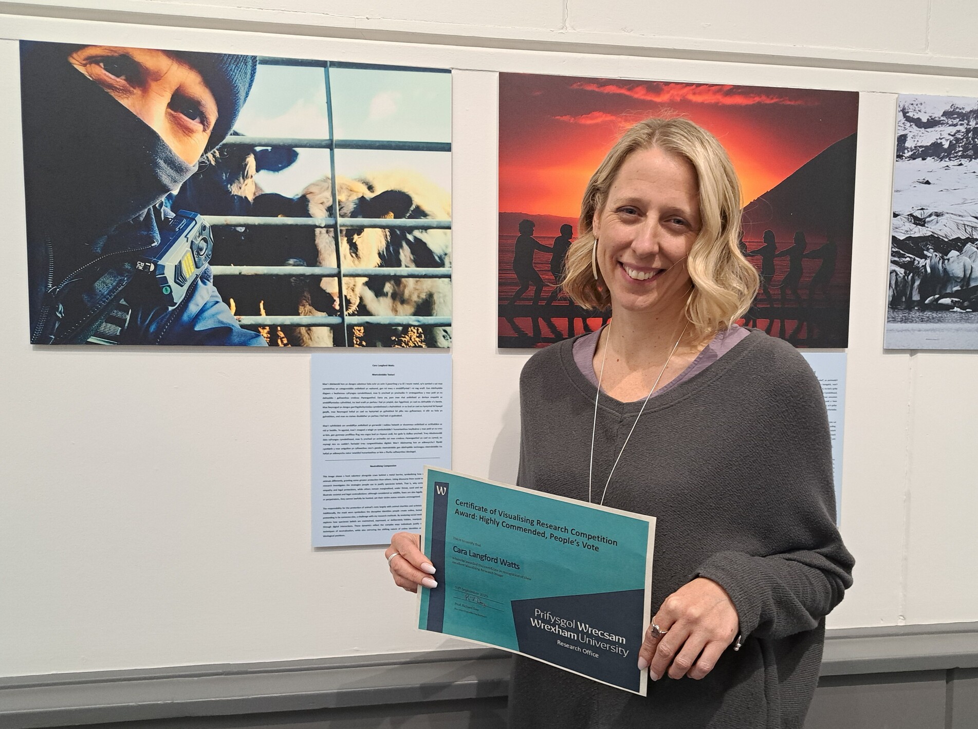 care standing next to their image on the wall holding a certificate